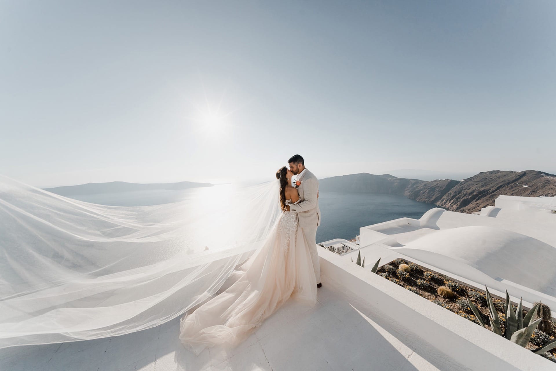 Stunning photoshooting of married couple kissing in front of Santorini’s Caldera